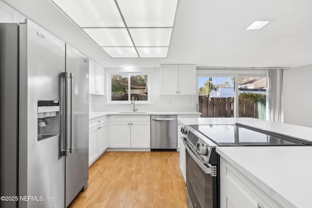 kitchen featuring stainless steel appliances, a sink, and white cabinets