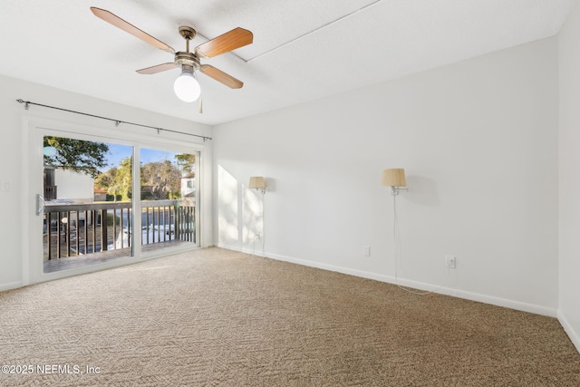 carpeted spare room with baseboards and a ceiling fan