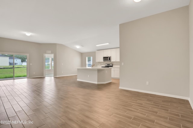 unfurnished living room with lofted ceiling, wood tiled floor, and baseboards