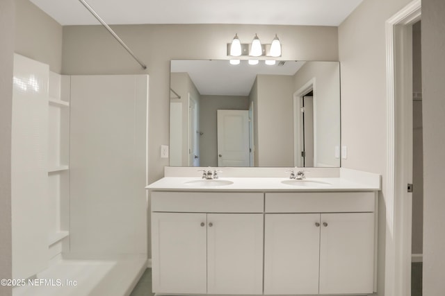 bathroom with double vanity, a shower, and a sink