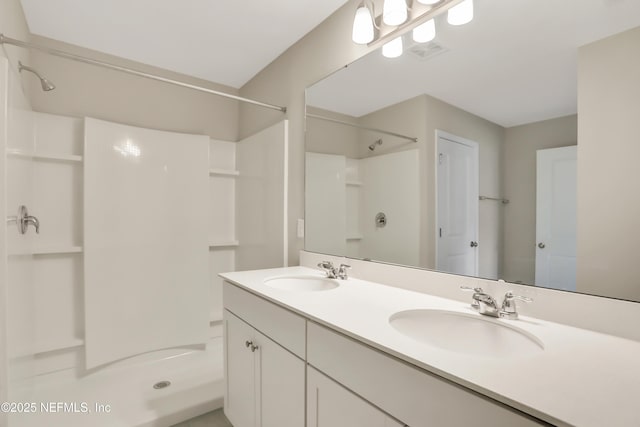 full bath featuring double vanity, walk in shower, a sink, and visible vents