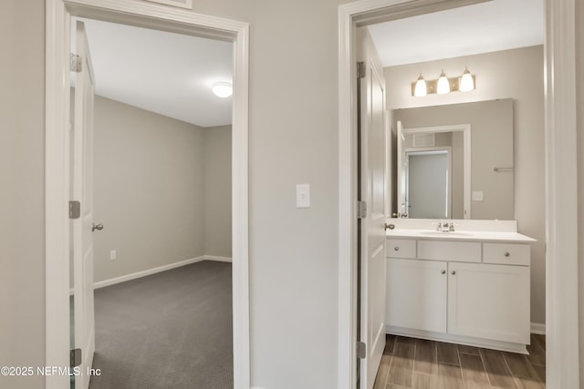 bathroom with baseboards, wood finished floors, and vanity