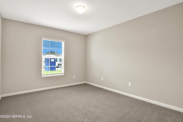 carpeted spare room featuring baseboards