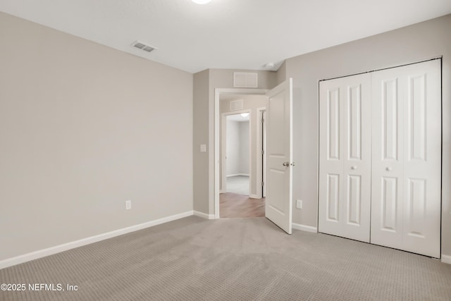 unfurnished bedroom with a closet, light colored carpet, visible vents, and baseboards