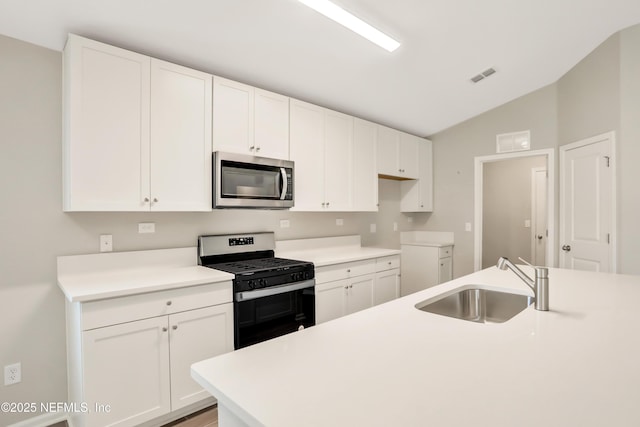 kitchen with stainless steel appliances, lofted ceiling, visible vents, white cabinetry, and a sink