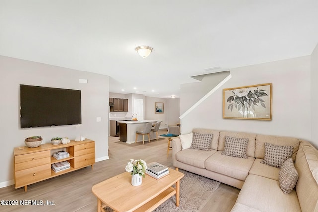 living room with light wood-style floors, baseboards, and recessed lighting