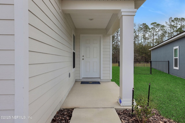 entrance to property featuring a yard and fence