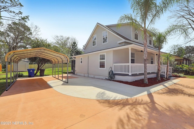 view of side of property featuring an outbuilding, covered porch, concrete driveway, a carport, and a shed