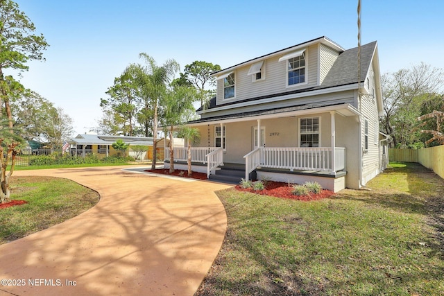 view of front facade featuring a porch, fence, driveway, and a front lawn