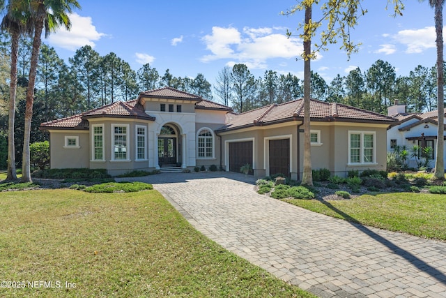 mediterranean / spanish-style home with a front lawn, an attached garage, and stucco siding