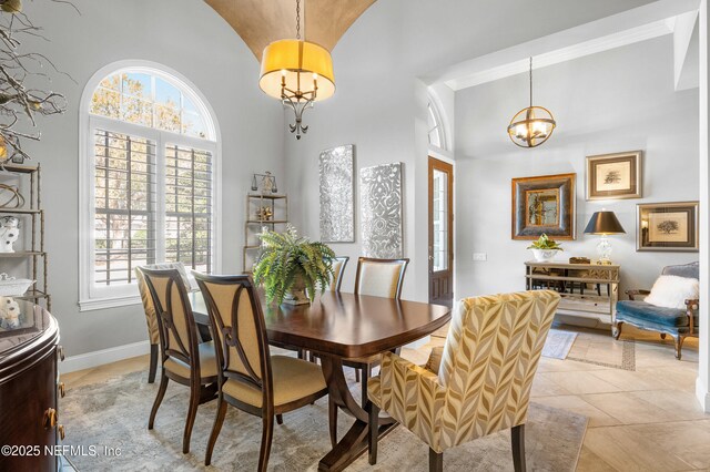 dining space featuring a chandelier, high vaulted ceiling, light tile patterned floors, and baseboards