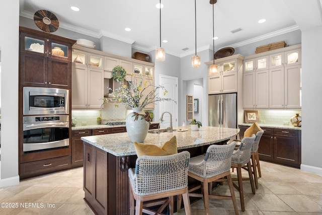 kitchen featuring stainless steel appliances, a center island with sink, a sink, and ornamental molding