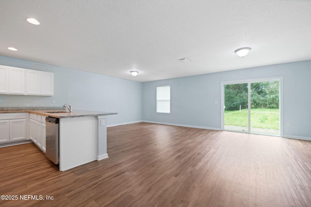 kitchen featuring white cabinets, dishwasher, open floor plan, wood finished floors, and a peninsula