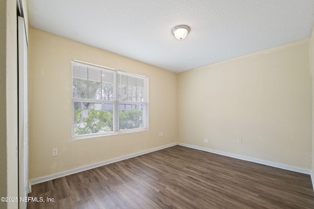 spare room with dark wood-style floors, a textured ceiling, and baseboards