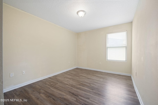 unfurnished room featuring dark wood-style floors, a textured ceiling, and baseboards