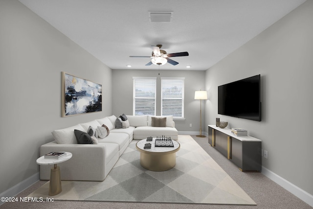 living area featuring visible vents, light colored carpet, a ceiling fan, and baseboards