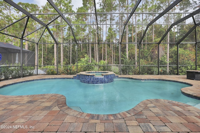 view of pool featuring a pool with connected hot tub, a patio area, and a lanai