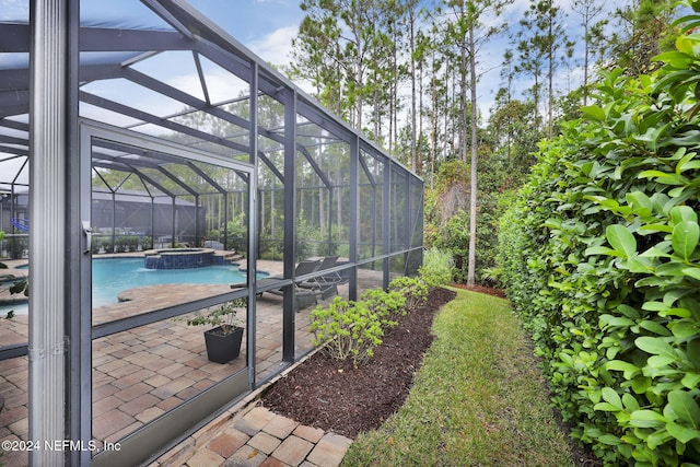 view of pool featuring a lanai, a pool with connected hot tub, and a patio