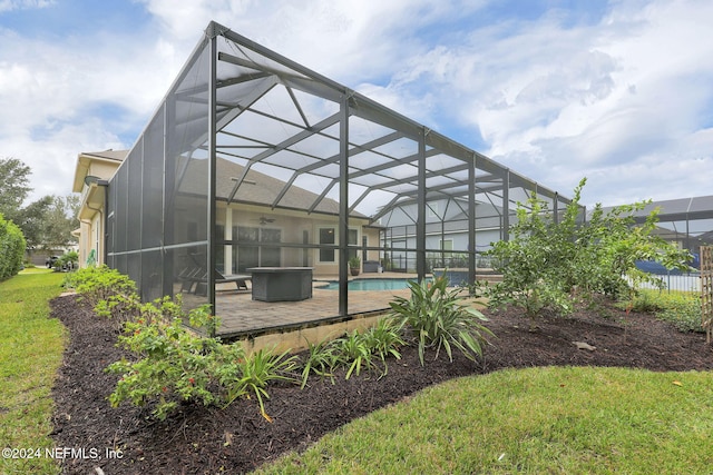 exterior space featuring glass enclosure, a patio area, a ceiling fan, and an outdoor pool