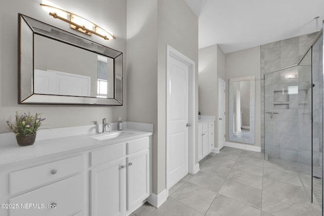 full bath with a tile shower, vanity, and baseboards