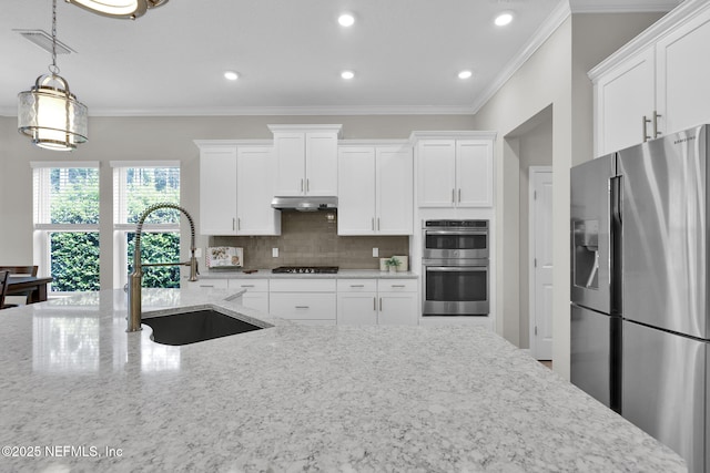 kitchen with under cabinet range hood, stainless steel appliances, a sink, visible vents, and decorative backsplash