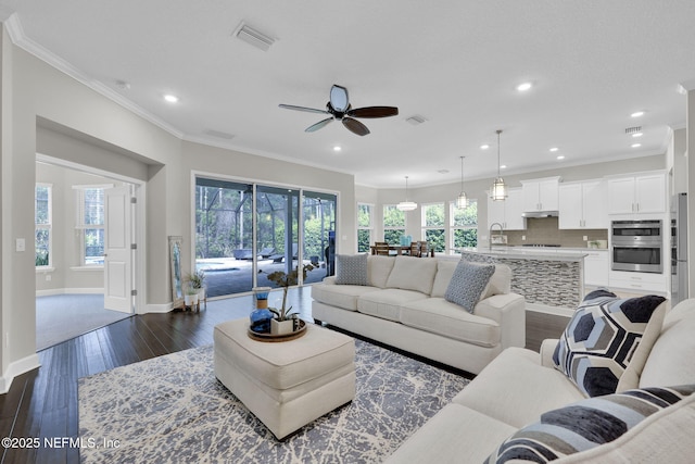 living room with dark wood finished floors, recessed lighting, visible vents, ornamental molding, and baseboards