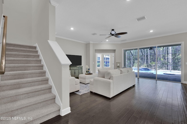 living area with stairway, visible vents, dark wood finished floors, and ornamental molding