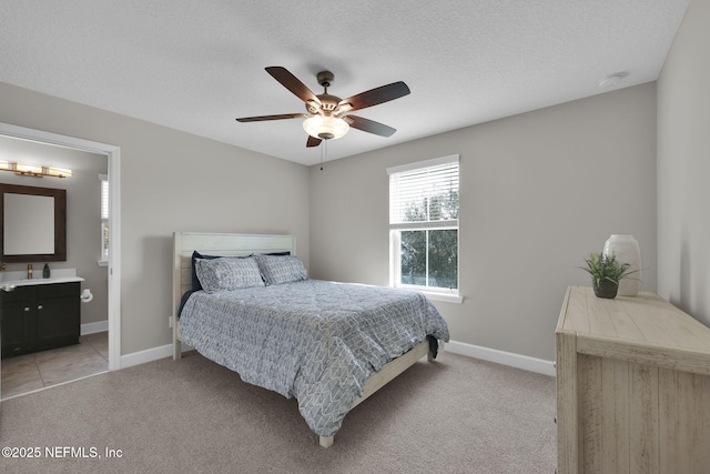 bedroom featuring light carpet, a textured ceiling, and baseboards