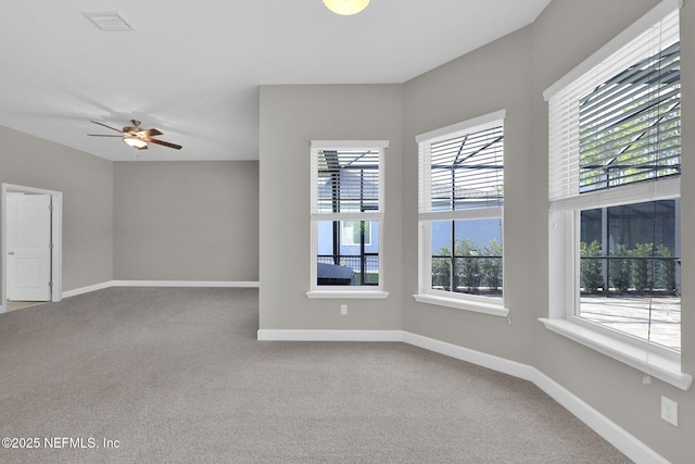 carpeted empty room featuring ceiling fan, visible vents, and baseboards