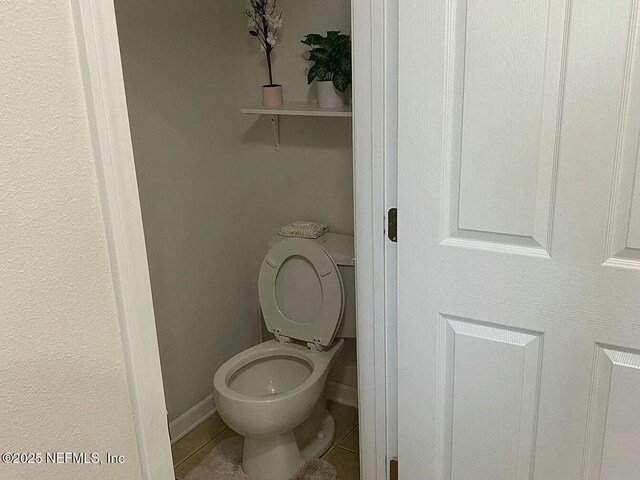 bathroom with tile patterned flooring, toilet, and baseboards