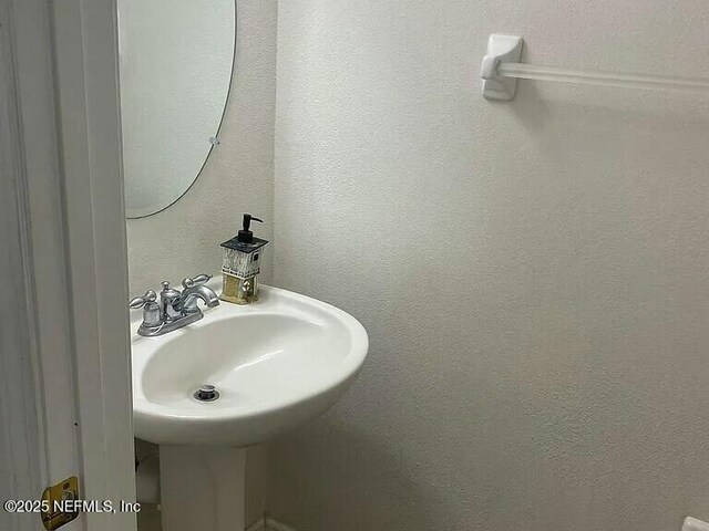 bathroom with a textured wall and a sink