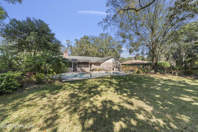 view of yard with a sunroom, fence, and an outdoor pool