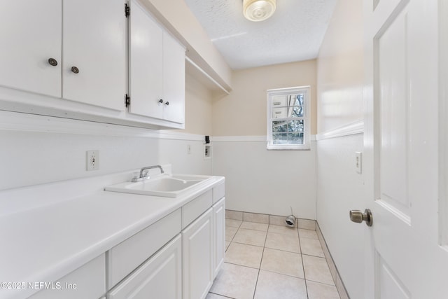 washroom with cabinet space, light tile patterned floors, a textured ceiling, washer hookup, and a sink