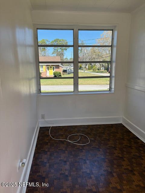 empty room featuring ornamental molding and baseboards