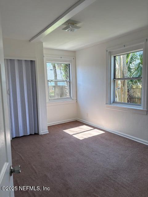 spare room featuring carpet floors and baseboards