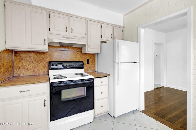 4804 Elizabeth Ter, Jacksonville, FL 32205 - kitchen featuring light tile patterned floors, electric stove, freestanding refrigerator, light countertops, and under cabinet range hood