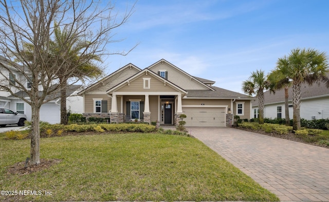 craftsman inspired home with decorative driveway, a front yard, stone siding, and an attached garage