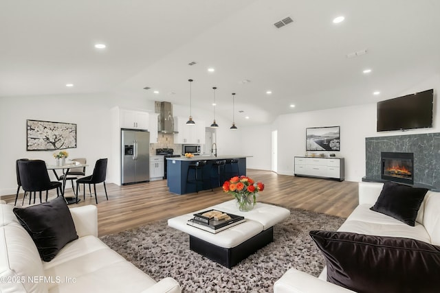 living area with light wood finished floors, visible vents, vaulted ceiling, and recessed lighting