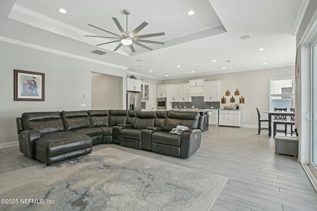 living room with visible vents, a tray ceiling, and ornamental molding