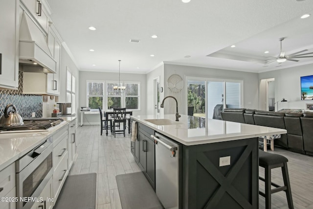 kitchen featuring a breakfast bar area, stainless steel appliances, decorative backsplash, wood tiled floor, and a sink