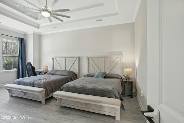 bedroom with crown molding, a raised ceiling, visible vents, wood finished floors, and baseboards