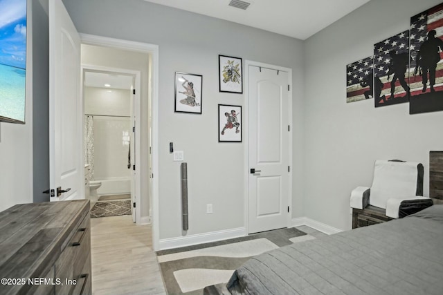 bedroom featuring ensuite bath, wood finished floors, visible vents, and baseboards