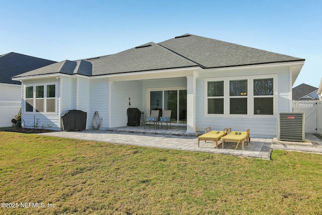 rear view of house featuring a shingled roof, a patio area, a yard, and fence