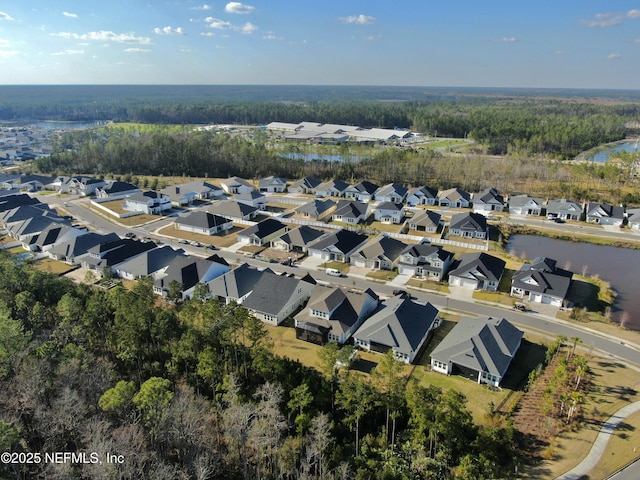 drone / aerial view with a residential view, a water view, and a wooded view