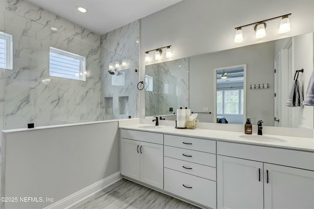 ensuite bathroom with a wealth of natural light, a sink, and a marble finish shower