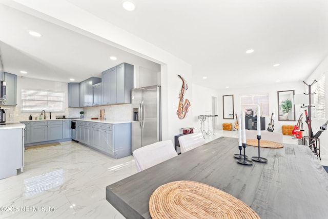 kitchen with marble finish floor, a healthy amount of sunlight, stainless steel fridge, and gray cabinetry