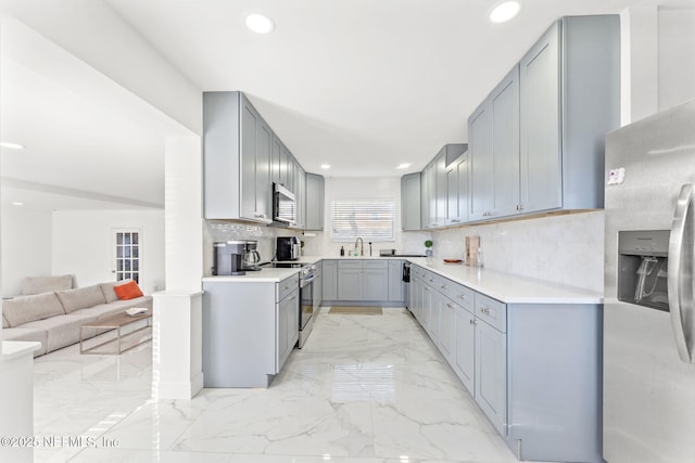 kitchen featuring open floor plan, marble finish floor, appliances with stainless steel finishes, and gray cabinetry