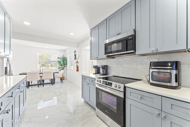 kitchen featuring gray cabinetry, marble finish floor, appliances with stainless steel finishes, light countertops, and tasteful backsplash