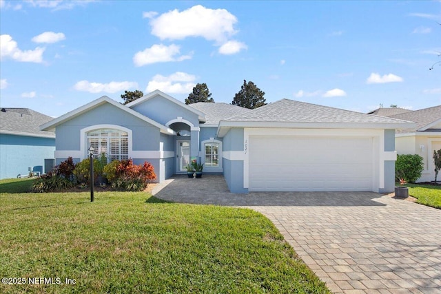 ranch-style house with decorative driveway, stucco siding, a shingled roof, a front yard, and a garage