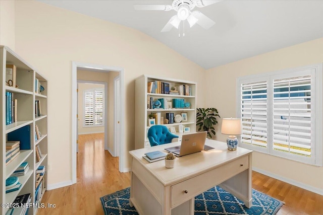 home office with vaulted ceiling, ceiling fan, light wood-type flooring, and baseboards